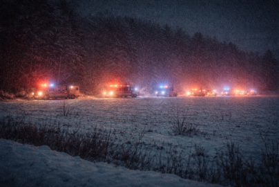 a grainy image of a line of emergency vehicles off in the distance parked along a snowy field