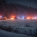 a grainy image of a line of emergency vehicles off in the distance parked along a snowy field